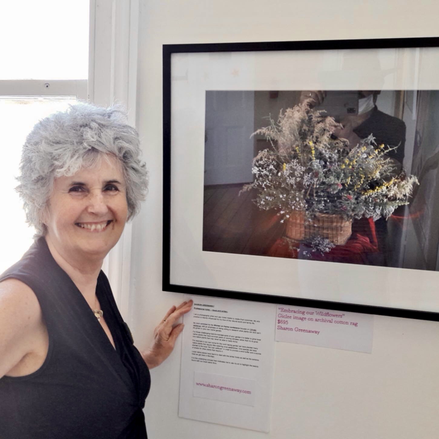 Sharon exhibiting a framed giclee image featuring local wildflowers. Inglewood, Victoria.