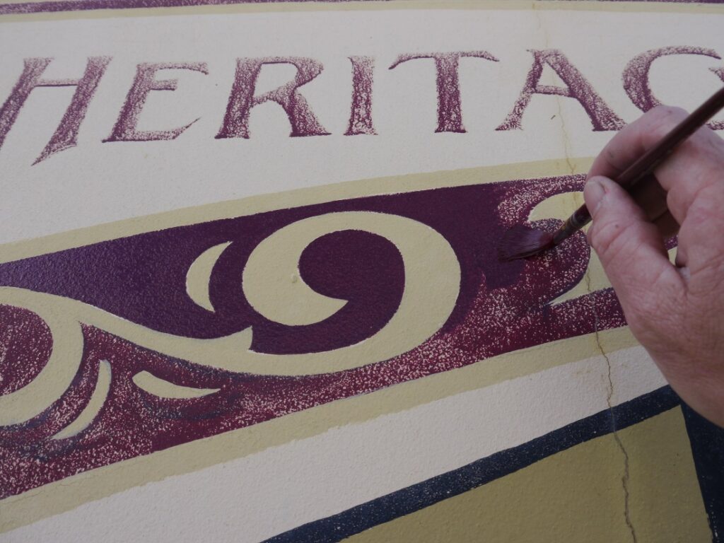 Hand painted heritage signs, Scrollwoork and lettering in burgundy on cream.