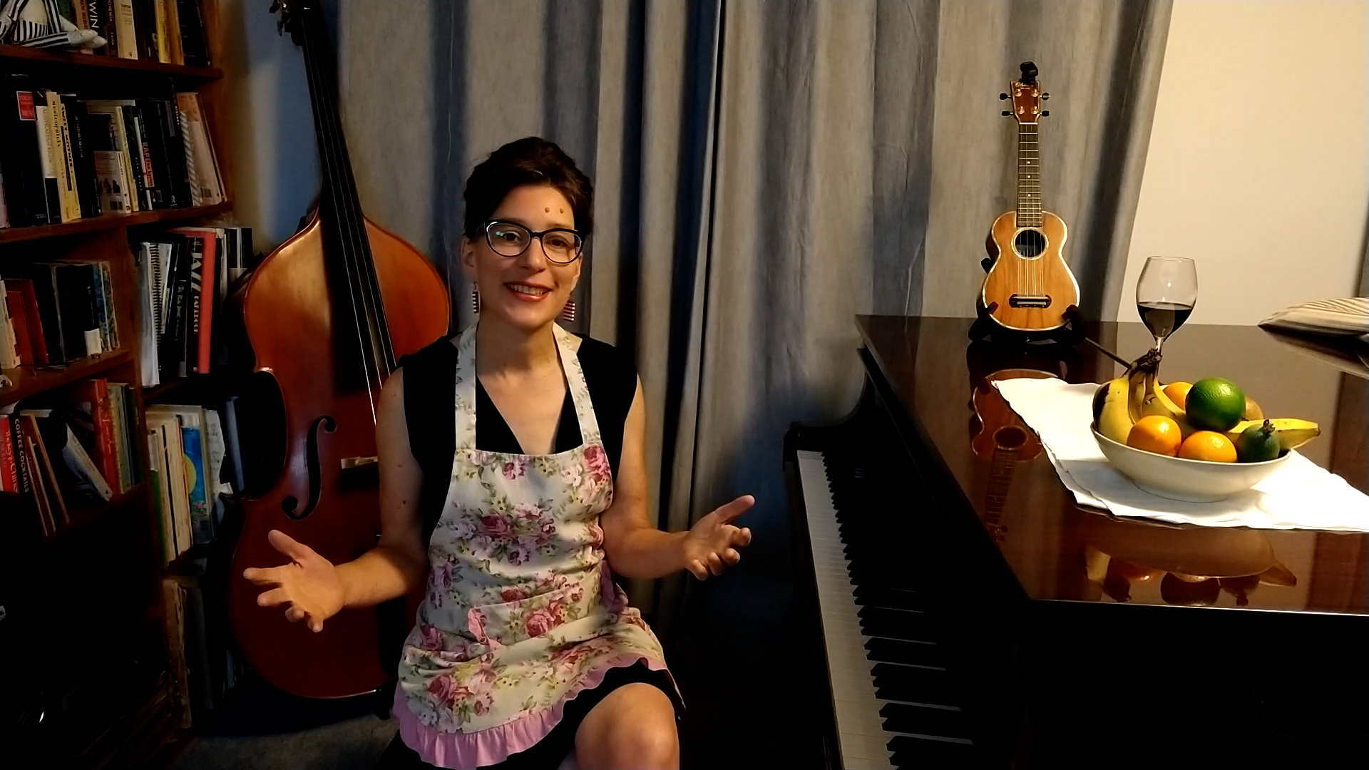 woman wearing apron seated next to a piano and double bass