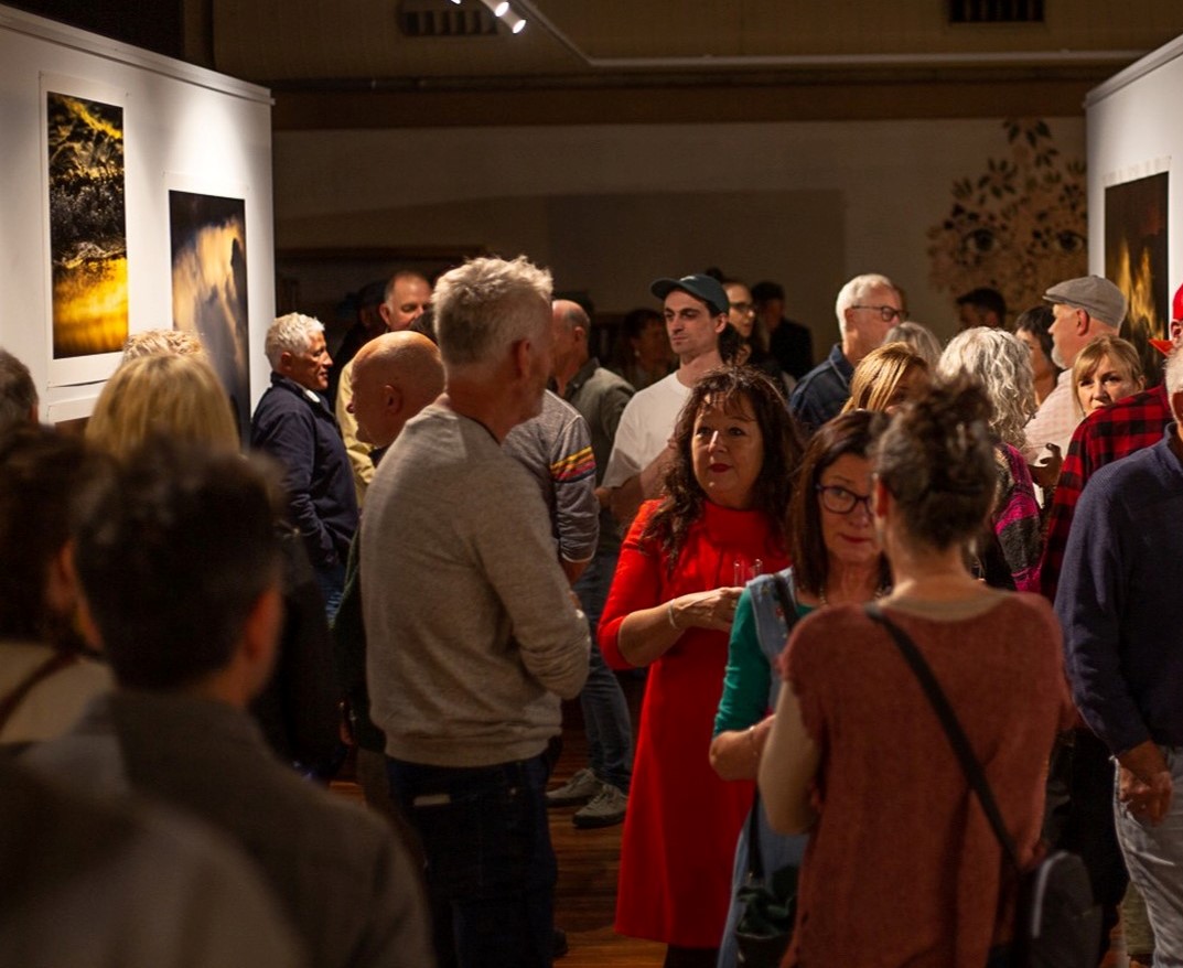 Many people standing and talking in a gallery