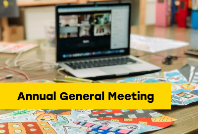 Annual General Meeting. Desk with laptop open to a meeting and artwork on the desk