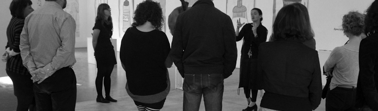 Black and white photo of people at a member event in a gallery.